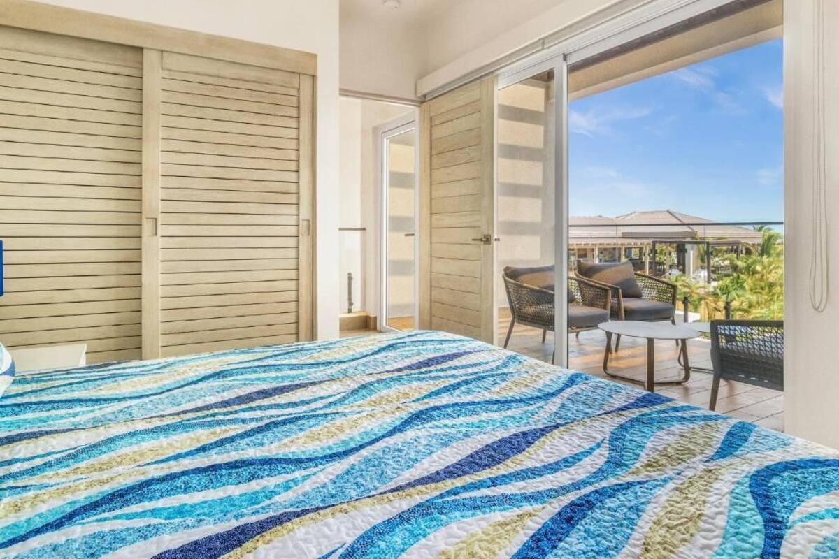A bedroom with a large bed, a sliding door to a balcony, and a view of the outside.