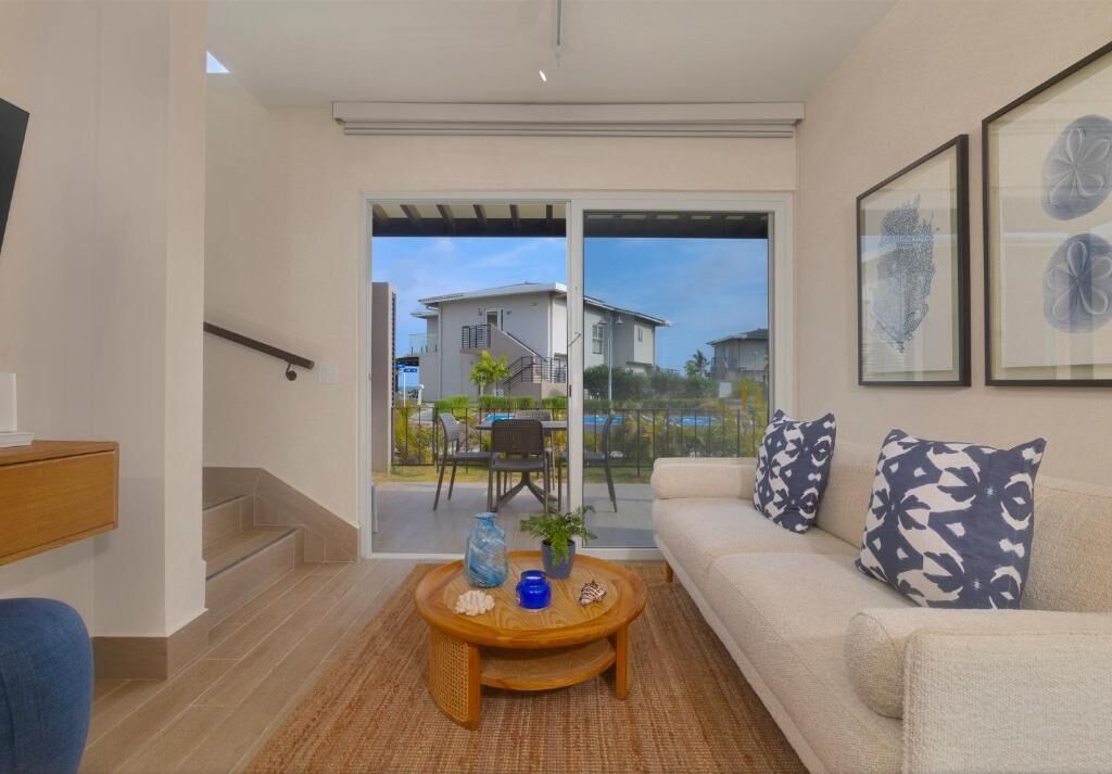 A modern living room with a sofa, coffee table, and a staircase leading to a balcony.