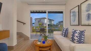 A modern living room with a sofa, coffee table, and a staircase leading to a balcony.