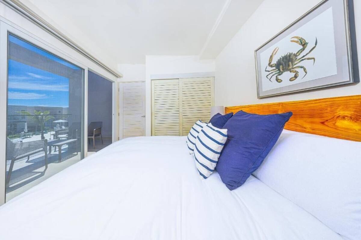 A bedroom with a large bed, a wooden headboard, a balcony with a view, and a framed picture on the wall.
