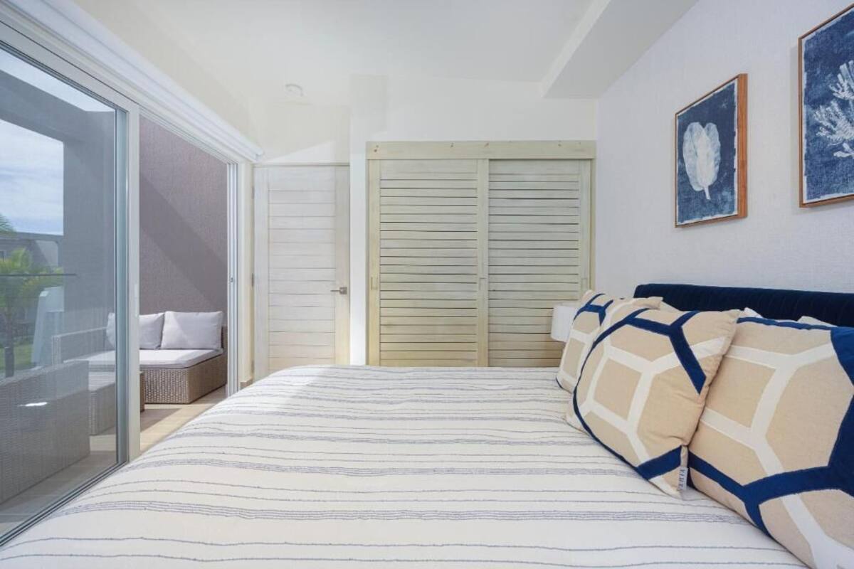 A bedroom with a large bed, a sliding glass door leading to a balcony, and a closet with sliding doors.