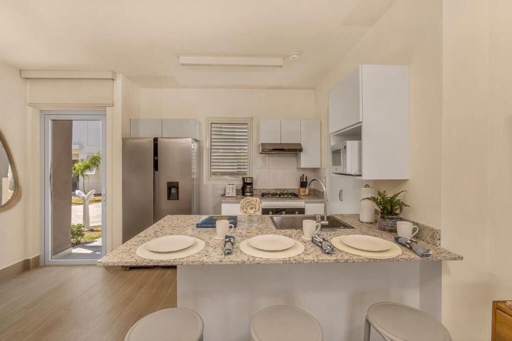 A modern kitchen with granite countertops, stainless steel appliances, and a central island with stools.