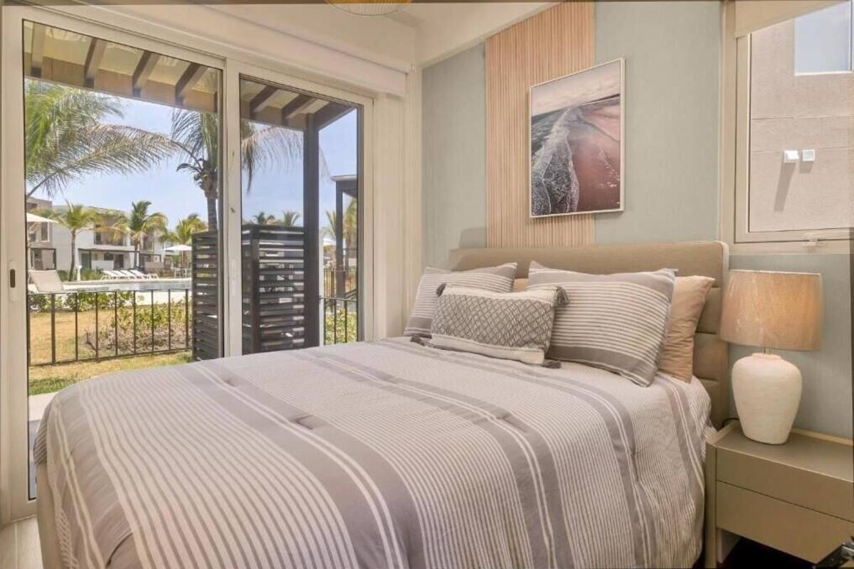 A bedroom with a bed, a nightstand, a lamp, and a painting on the wall.