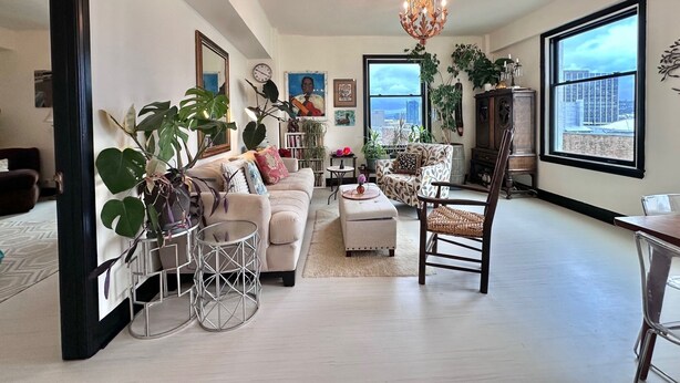 A spacious living room with a large window, a chandelier, and various plants. - 2-bedroom condo in enchanting San Francisco with views and fitness room (San Francisco)