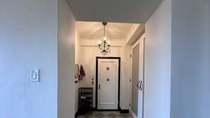 A hallway with a checkered floor, a chandelier, a door, and a small shelf with shoes. - 2-bedroom condo in enchanting San Francisco with views and fitness room (San Francisco)