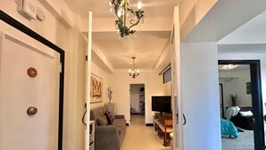 A hallway leading to a living room with a sofa, TV, and chandelier. - 2-bedroom condo in enchanting San Francisco with views and fitness room (San Francisco)