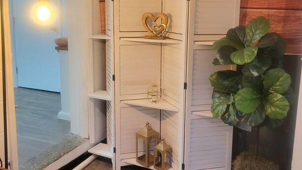 Een witte, meerlaagse opbergunit met decoratieve objecten voor een houten wand.