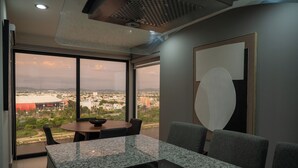 Ein moderner Konferenzraum mit einem großen Tisch, bequemen Stühlen und Blick auf eine Stadtlandschaft durch große Fenster.