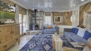 A cozy living room with a fireplace, comfortable seating, and a large window overlooking a scenic landscape. - Sleeps 25, 5 Homes, Fire Pit, Spring Fed Waterfront (Ingram)