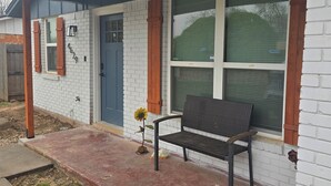 A house with a porch, a bench, and a flower.