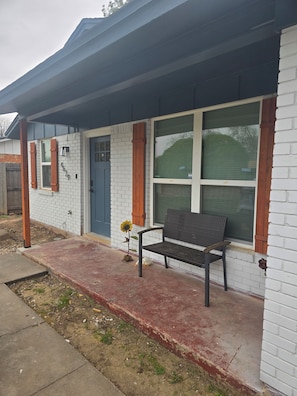 A house with a porch, a bench, and a flower.
