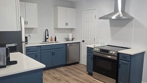 A modern kitchen with white cabinets, a stainless steel range, and a dishwasher.