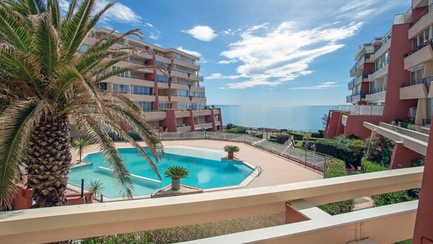 A hotel with a pool, palm trees, and a view of the sea. - "Le Pajo" Seafront apartment, T3 Air-conditioned - Wifi, Swimming pool and parking lot (Sète)
