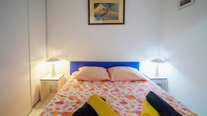 A hotel room with a bed, two bedside lamps, a framed picture on the wall, and towels on the bed. - "Le Pajo" Seafront apartment, T3 Air-conditioned - Wifi, Swimming pool and parking lot (Sète)