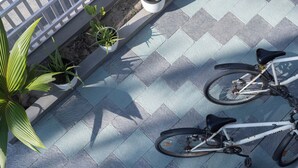 Deux vélos sont garés sur une surface pavée, à proximité de plantes en pot.