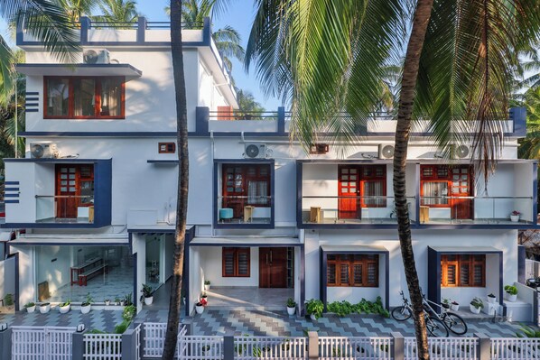 A multi-story residential building with balconies, large windows, and a tiled patio area.