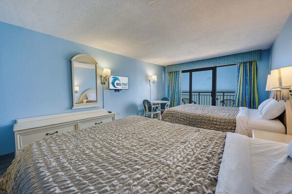 Une chambre d’hôtel avec deux lits, un bureau, une chaise, une grande fenêtre avec des rideaux et une enseigne indiquant « Big Fish Rental ».