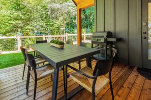 Eine Außenpatio mit Tisch, Stühlen, einem Grill und Blick auf einen Garten.