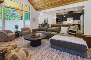 Ein modernes Wohnzimmer mit einer Eckcouch, einem runden Couchtisch und Blick zur Küche.