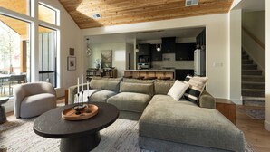 Een moderne woonkamer met een modulaire bank, een salontafel, en een eethoek met tafel en stoelen.