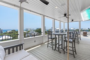 A covered outdoor deck with a table and chairs, a rope, and a view of the ocean and buildings. - All Decked Out Seagrove 30a Gulf View Steps from Beach w Private Pool & Spa (Santa Rosa Beach)