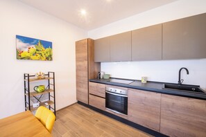 Eine moderne Küche mit Holzausstattung, einer schwarzen Arbeitsplatte und einem Edelstahlbackofen.