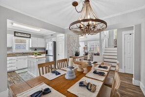 A spacious dining area with a wooden table set for four, surrounded by white cabinetry and a stone accent wall. - 30A Sea-Renity! Private heated Pool, Spa & Beach Dayz Bliss! Pets Allowed. (Santa Rosa Beach)