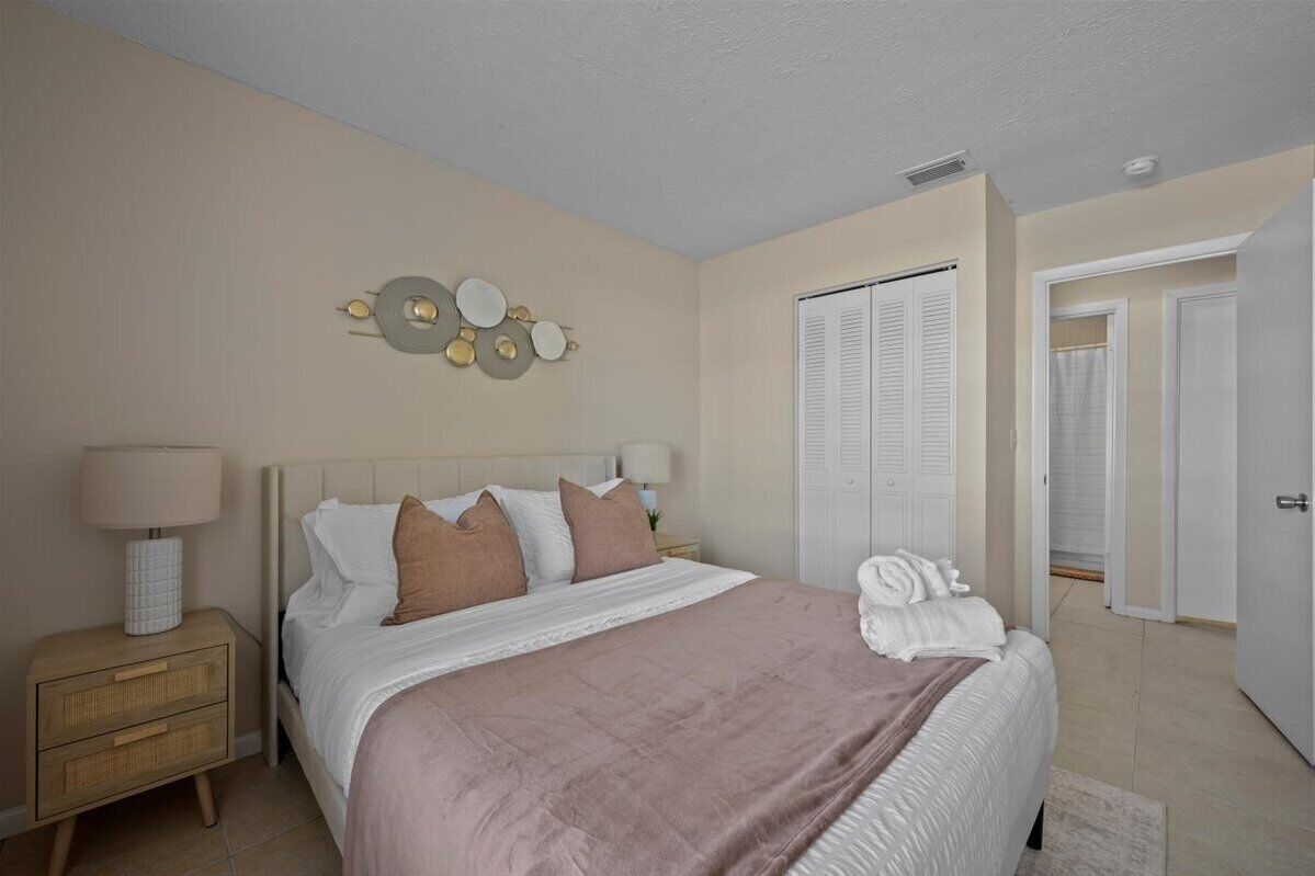 Une chambre à coucher comprenant un lit, des tables de chevet, un élément de décoration murale et une armoire.