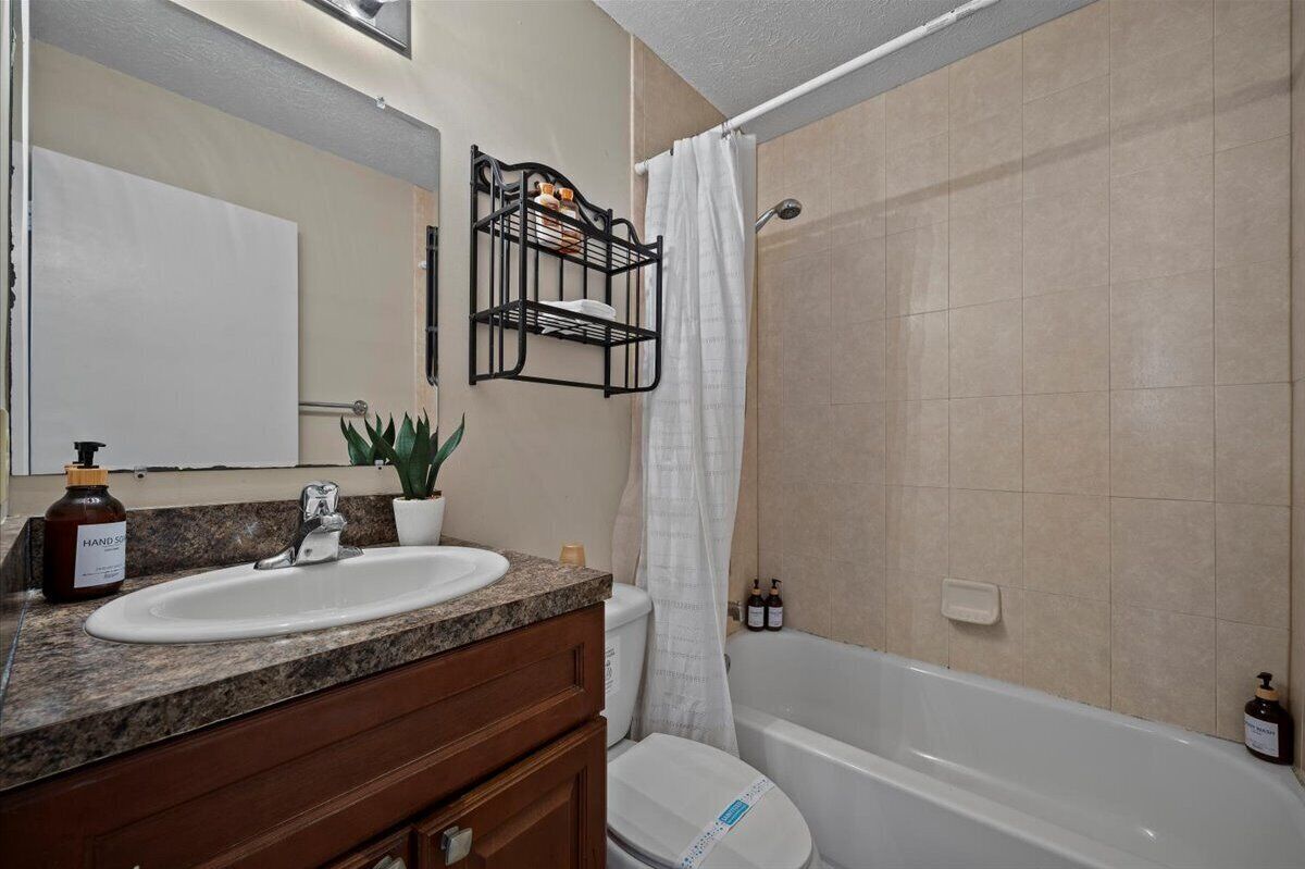 A bathroom with a sink, mirror, vanity, toilet, and bathtub.