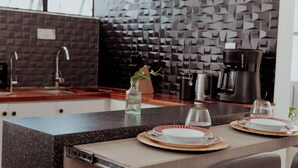 A modern kitchen with a granite countertop, a coffee maker, and a decorative vase with a plant. - Comfort apt in Oaxaca centro | Large kitchen, TV room + 100MB internet + KS bed (Oaxaca de Juárez)