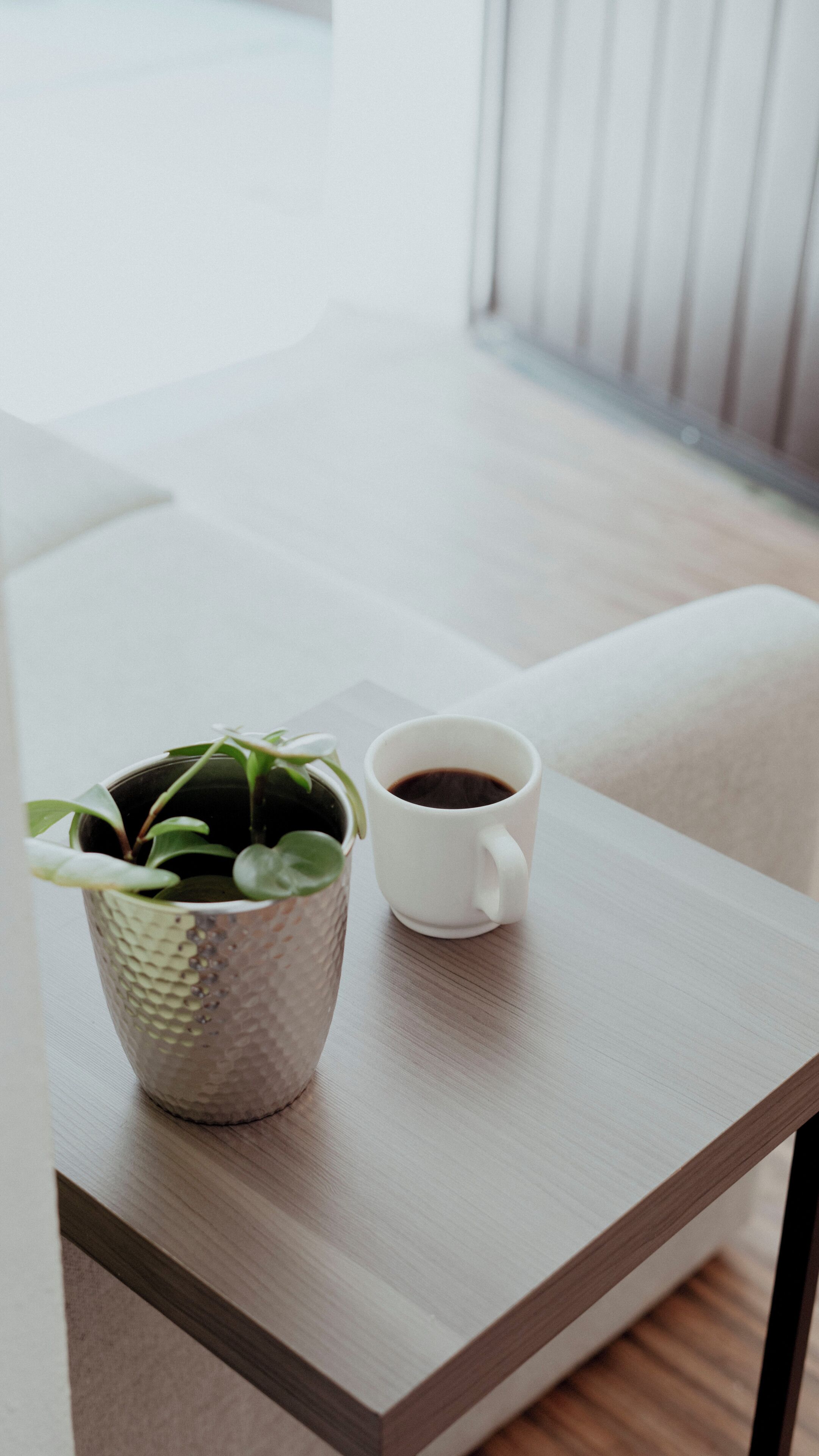 A small table with a white mug and a textured plant pot.