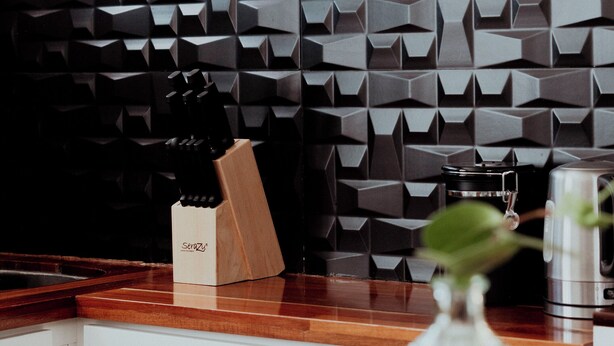 A kitchen with a modern geometric backsplash, a wooden cutting board, and a coffee maker on the counter. - Comfort apt in Oaxaca centro | Large kitchen, TV room + 100MB internet + KS bed (Oaxaca de Juárez)