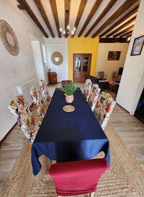 Zona pranzo con un tavolo lungo, sedie a fantasia, una pianta al centro e una panca rossa.