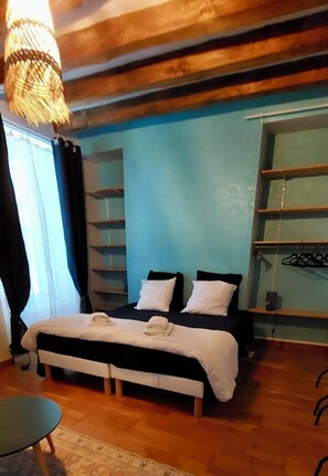 Una camera da letto con un letto, una sedia, una lampada a sospensione e mensole a parete.