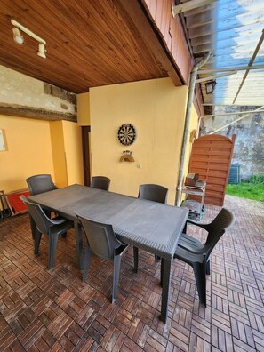Un patio coperto con tavolo e sedie, un bersaglio da gioco e una zona barbecue.