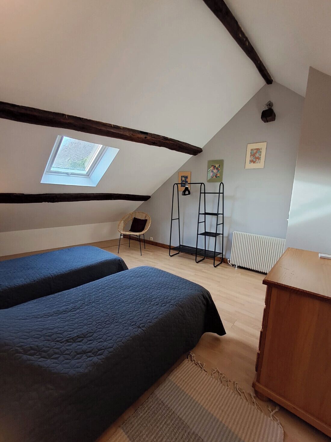 Quarto de sótão pequeno e acolhedor, com duas camas, um claraboia, um radiador e um armário de madeira.