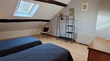 Quarto de sótão pequeno e acolhedor, com duas camas, um claraboia, um radiador e um armário de madeira.
