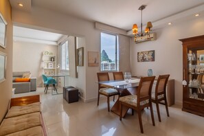 A modern hotel room with a dining area, a sofa, a small table, and a view of the city. - Charm in Copacabana Stc1002 (Rio de Janeiro)