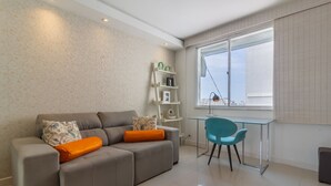 A modern living room with a grey sofa, orange cushions, a glass table, and a blue chair. - Charm in Copacabana Stc1002 (Rio de Janeiro)