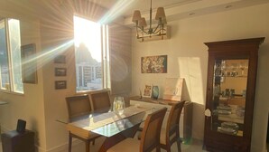 A dining area with a glass table, wooden chairs, a chandelier, and a cabinet with glassware. - Charm in Copacabana Stc1002 (Rio de Janeiro)