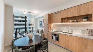 A modern kitchen with wooden cabinets, a built-in oven, and a dining area with a round table and chairs. - Crosby Miami WTC 1BR/1BA Cozy #304 (Miami)