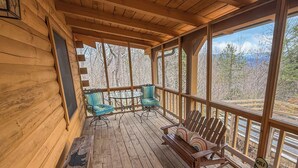 A wooden deck with a bench and two chairs, a wooden railing, and a view of trees and mountains. - Relax @ Benny Bear Cabin, WNC's newest addition • 2 Bed 2 Bath • Family Friendly (Bryson City)