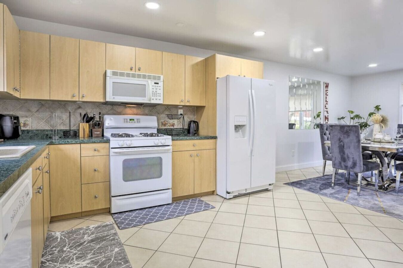 A modern kitchen with wooden cabinets, a white stove, a microwave, and a refrigerator.