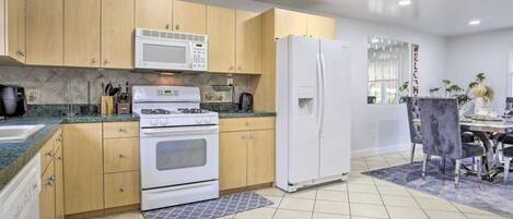 A modern kitchen with wooden cabinets, a white stove, a microwave, and a refrigerator.
