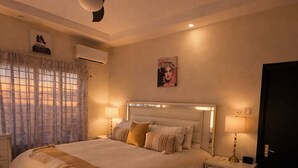 A bedroom with a bed, bedside tables, a nightstand, a ceiling fan, and a door. - Pyramid Tranquility/Luxury Retreat in Ocho Rios, St. Ann (Ocho rios)