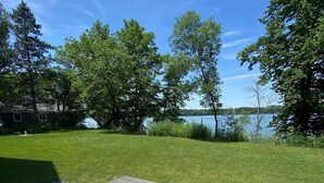 Eine Außenpatio mit Picknicktisch und Bank, umgeben von einer gepflegten Rasenfläche und Bäumen, mit Blick auf einen See.