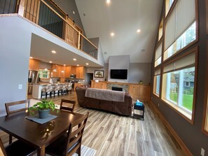 Un'ampia zona giorno in stile loft con un tavolo da pranzo, un divano e una cucina sullo sfondo.