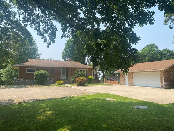 Una propiedad residencial con una casa de ladrillo, un garaje y un césped bien cuidado.