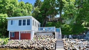 Ein Haus mit einem Steg, der ins Wasser hineinreicht, umgeben von einer Steinmauer und einer Holzterrasse.