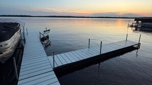Eine Holzsteg, der ins ruhige Wasser führt, mit einem Boot an der linken Seite vertäut.